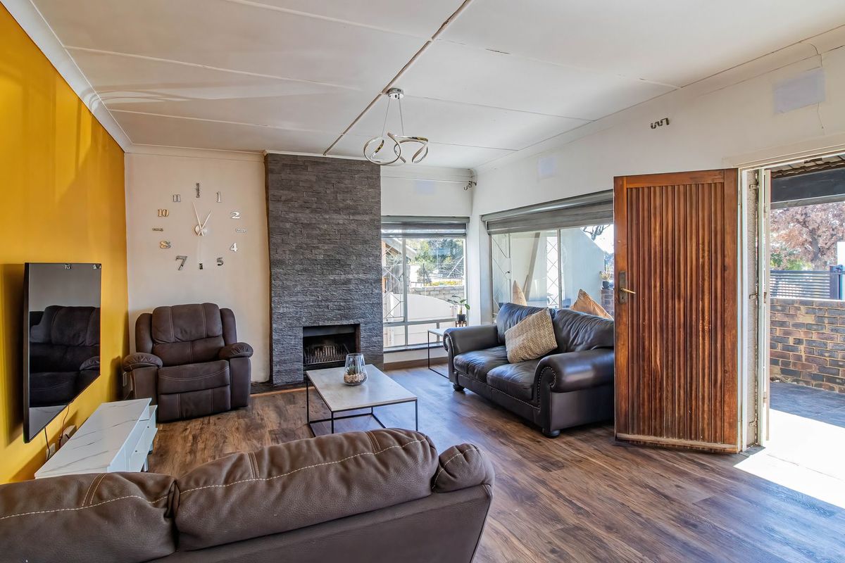 A living room featuring a stone-clad fireplace, laminate flooring, and direct access to an outdoor patio area.