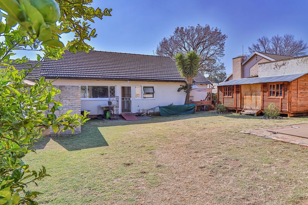 Rear view of the property featuring a spacious garden, swimming pool with cover, and a detached wooden outbuilding.