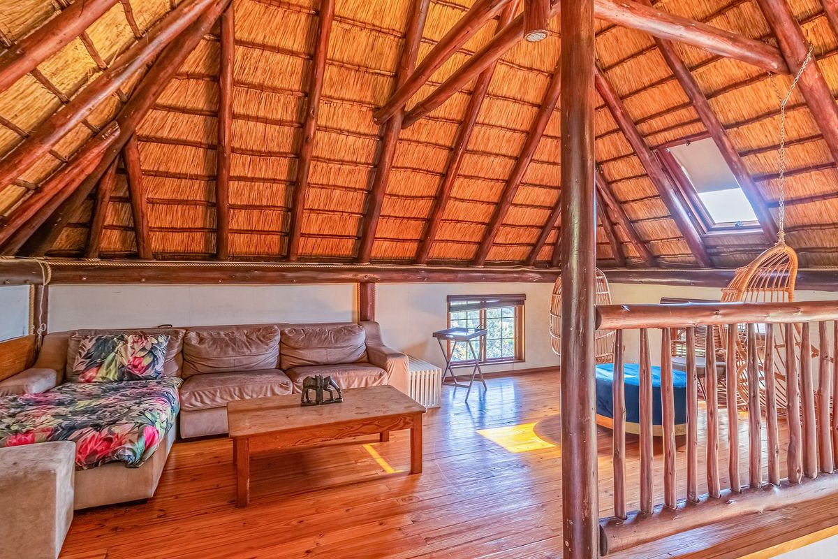 Spacious loft living area featuring a high vaulted thatched ceiling with exposed timber rafters, wooden flooring, and a skylight.