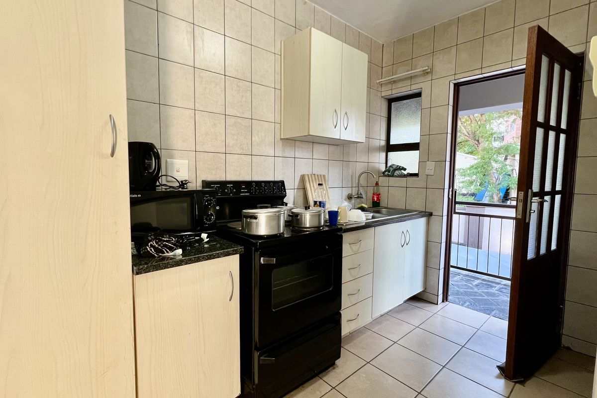 A functional kitchen featuring tiled walls, built-in cabinetry, a freestanding stove, and direct access to an outdoor balcony area.