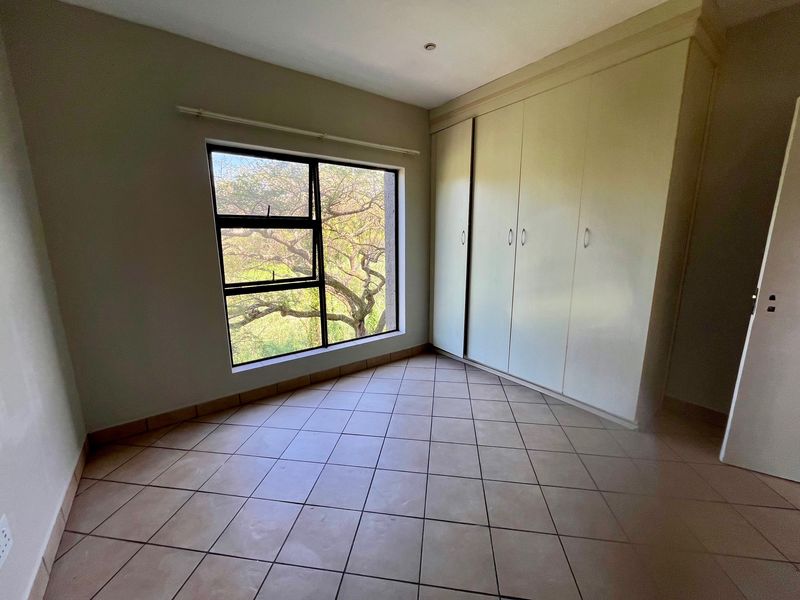 A bright, empty bedroom featuring neutral tiled flooring and ample built-in cupboard storage, offering a clean canvas for personalization.