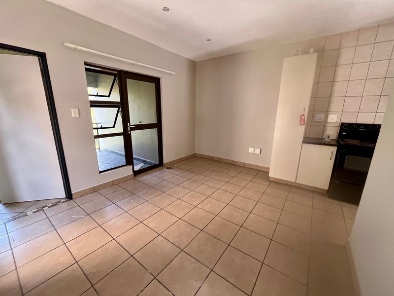 An open-plan living and kitchen area featuring tiled flooring, built-in cabinetry, and direct access to an outdoor balcony through a glass door.