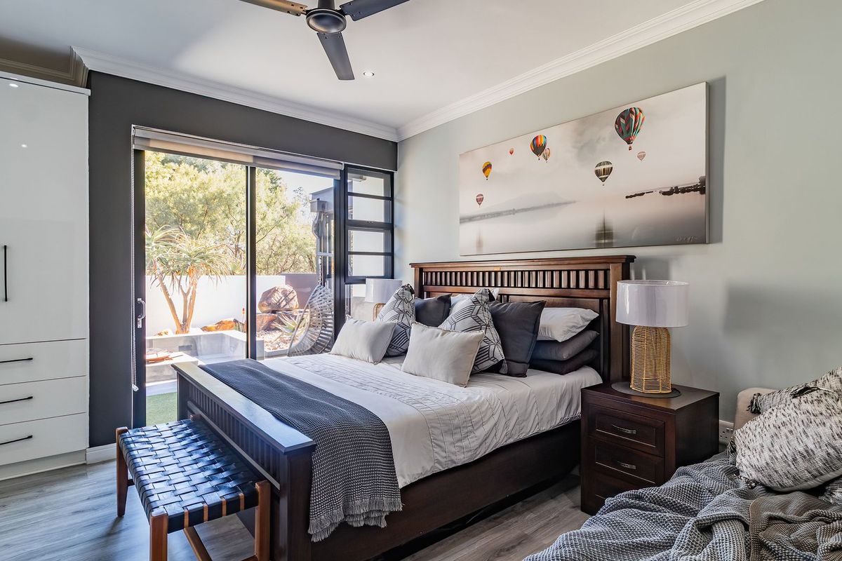 A well-maintained bedroom featuring built-in cupboards, laminate flooring, and a sliding glass door providing direct access to the outdoor area.