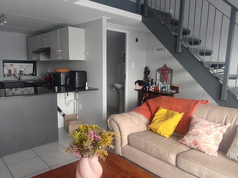 Open-plan living area featuring a kitchen with granite countertops, tiled flooring, and a staircase leading to the upper level.