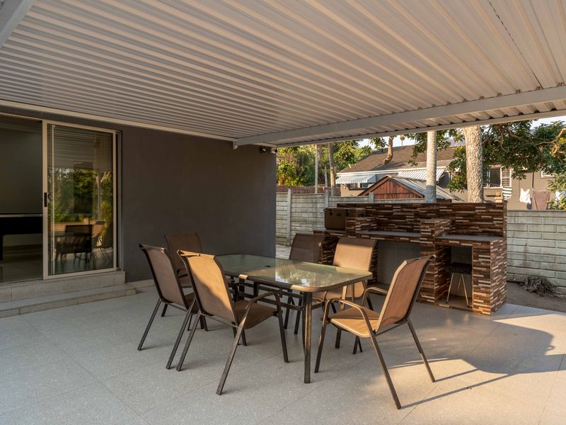 Covered outdoor patio featuring a built-in brick braai, tiled flooring, and direct access to the interior through sliding glass doors.