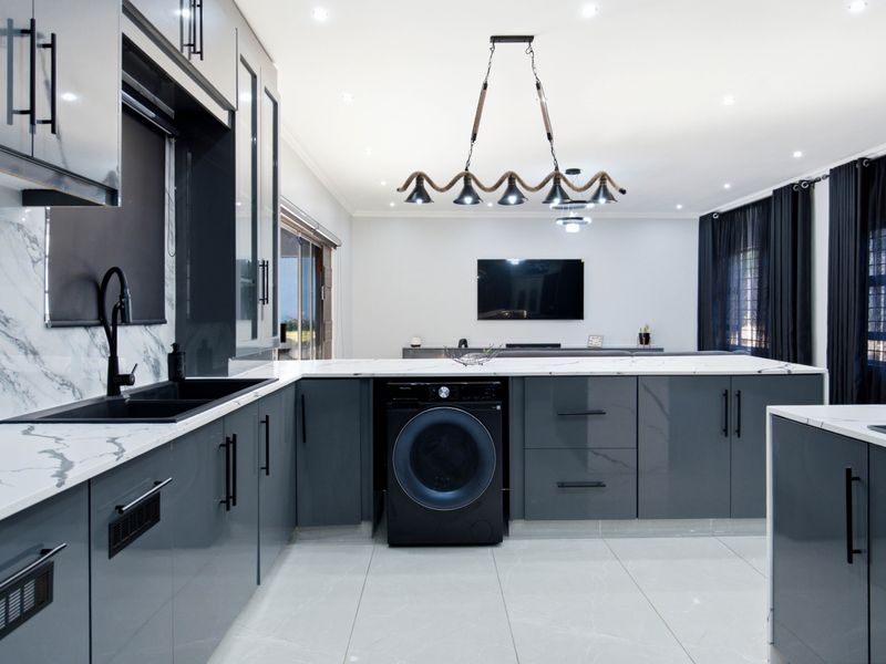 Modern open-plan kitchen featuring sleek grey cabinetry, marble-effect countertops, integrated appliances, and high-quality porcelain floor tiles in a contemporary living space.