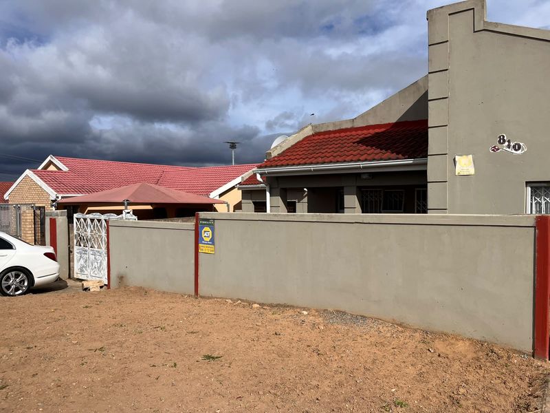 Front exterior view of the property featuring a perimeter wall, security gate, and tiled roof structure.