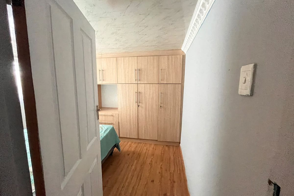 Bedroom featuring light wood-finish built-in cupboards, laminate flooring, and decorative ceiling cornice.