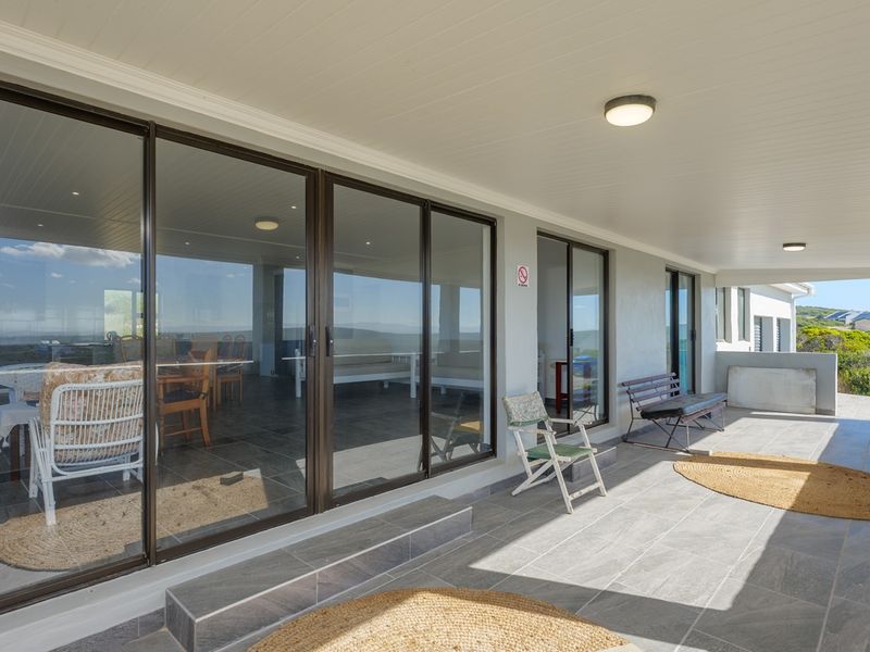 A spacious covered patio featuring large sliding glass doors, tiled flooring, and recessed ceiling lighting, offering a seamless transition to the outdoor area.