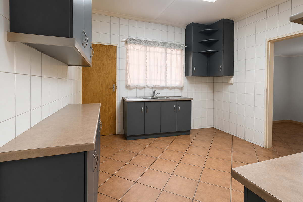 A functional kitchen featuring dark grey cabinetry, laminate countertops, tiled splashbacks, and ceramic floor tiles, offering a clean and practical workspace.