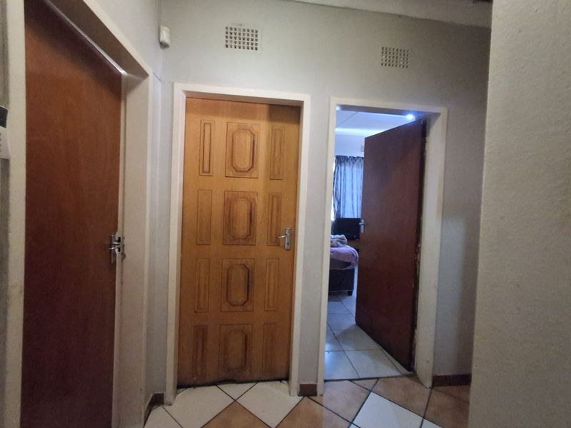 A functional hallway featuring tiled flooring and multiple wooden doors providing access to adjacent rooms.