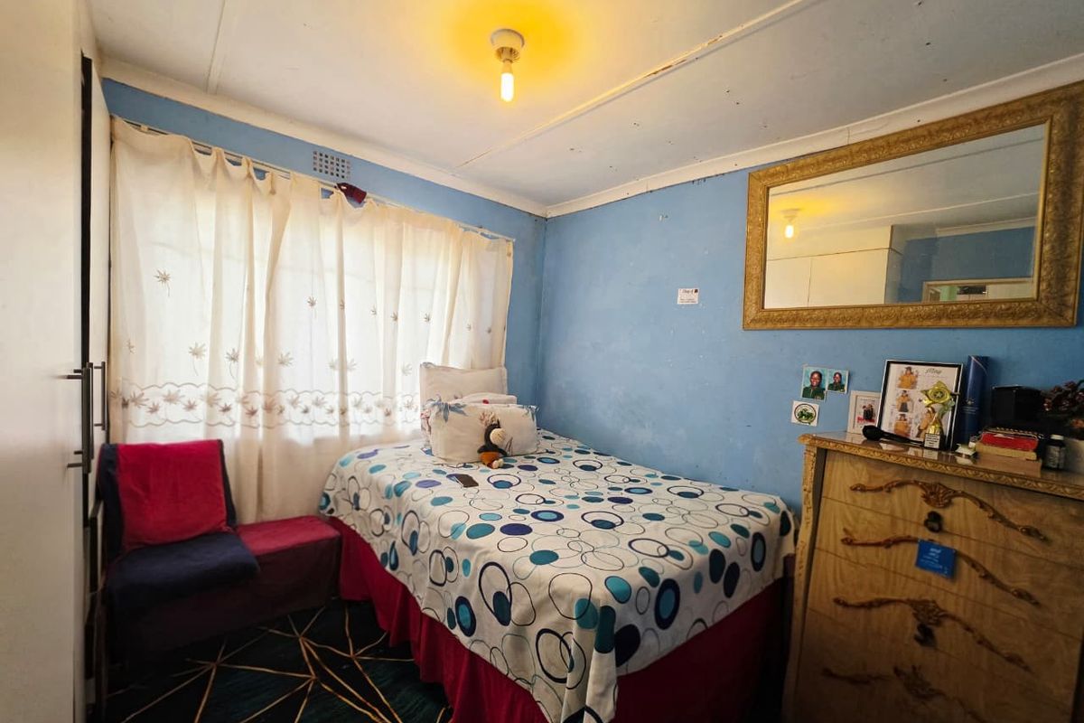 A compact bedroom featuring a built-in wardrobe and blue painted walls, requiring cosmetic updates to improve the overall finish and condition.