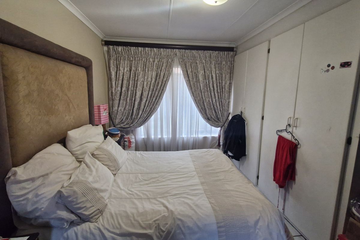 A functional bedroom featuring built-in cupboards and window treatments, offering a neutral base for potential interior updates.