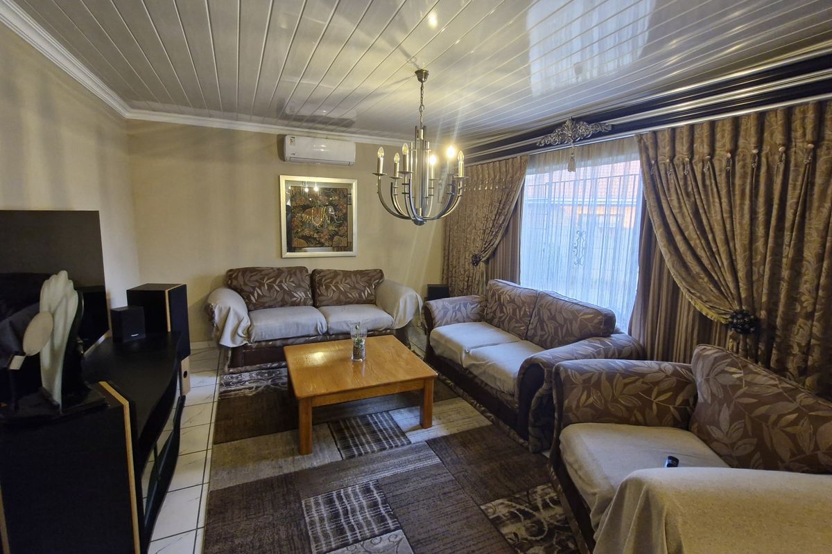 A comfortable living room featuring tiled flooring, a glossy ceiling finish, and a wall-mounted air conditioning unit.