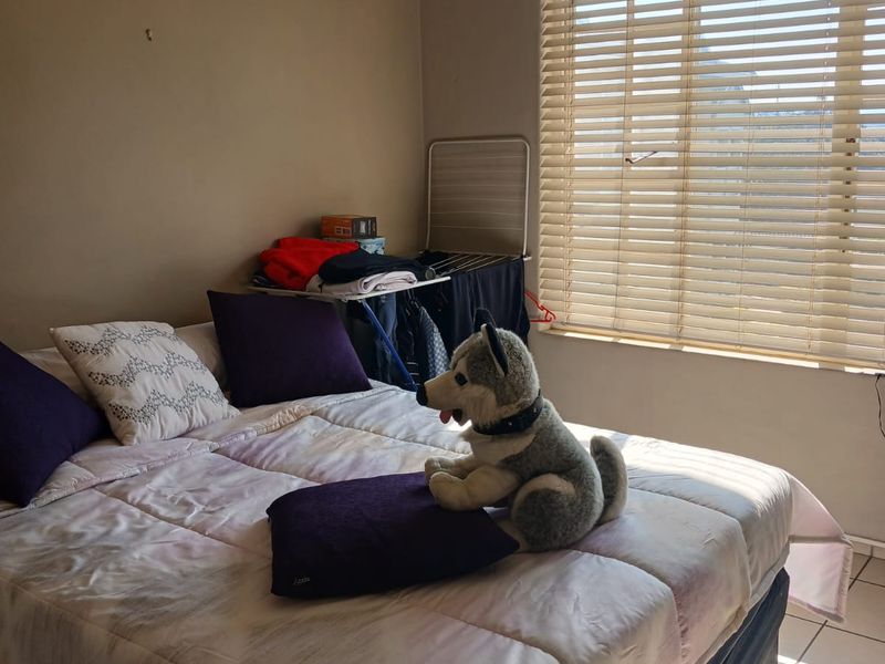 A bedroom featuring tiled flooring, a ceiling fan, and venetian blinds, providing a functional space with natural light.