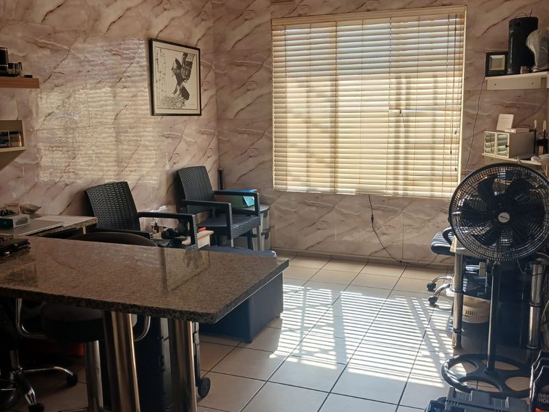 A living area featuring marble-effect wall cladding, tiled flooring, and venetian blinds, providing a functional space with natural light.