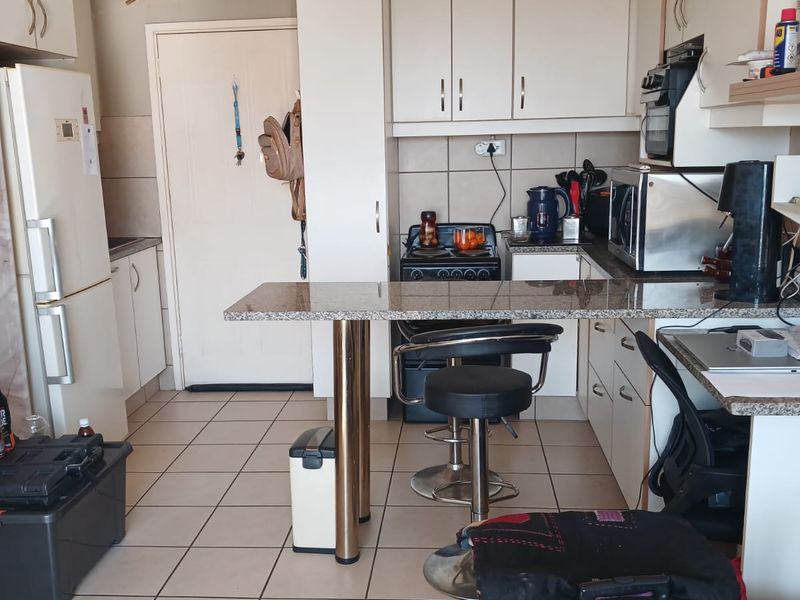 A functional kitchen featuring built-in cabinetry, granite countertops with a breakfast bar, and ceramic floor tiles, providing a practical layout for daily use.