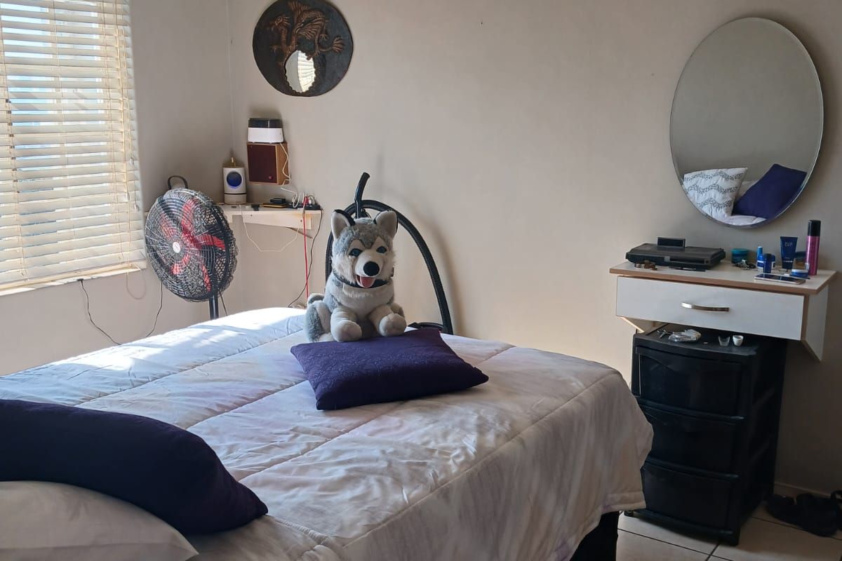 A bedroom featuring tiled flooring, a ceiling fan, and a wall-mounted vanity unit with a mirror.