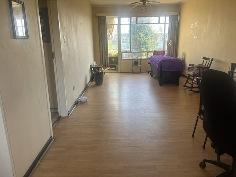 Spacious living area featuring laminate flooring, a ceiling fan, and a large sliding glass door providing access to the balcony.