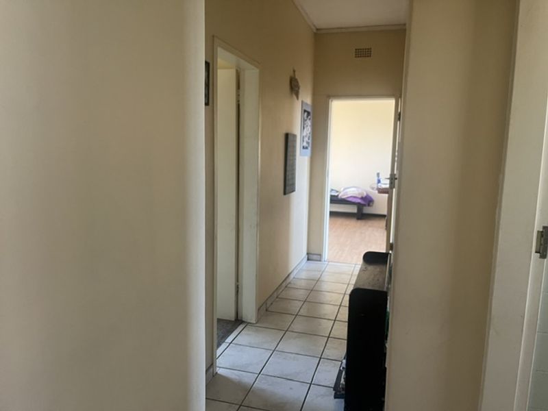 A functional hallway with tiled flooring providing access to adjacent rooms within the apartment.