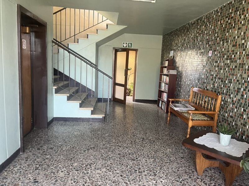 Communal apartment building lobby featuring a staircase, elevator access, terrazzo flooring, and a decorative mosaic tile wall.
