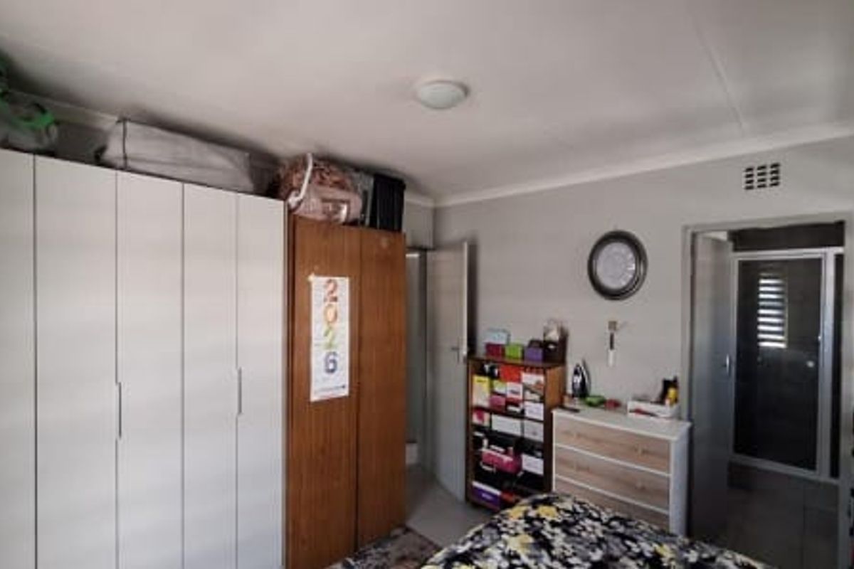 A bedroom featuring built-in cupboards and direct access to an en-suite bathroom, offering a functional layout with neutral wall finishes.