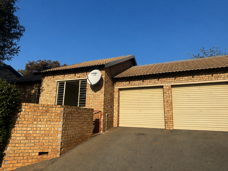 Front exterior view of a face brick house featuring a double garage, tiled roof, and paved driveway.