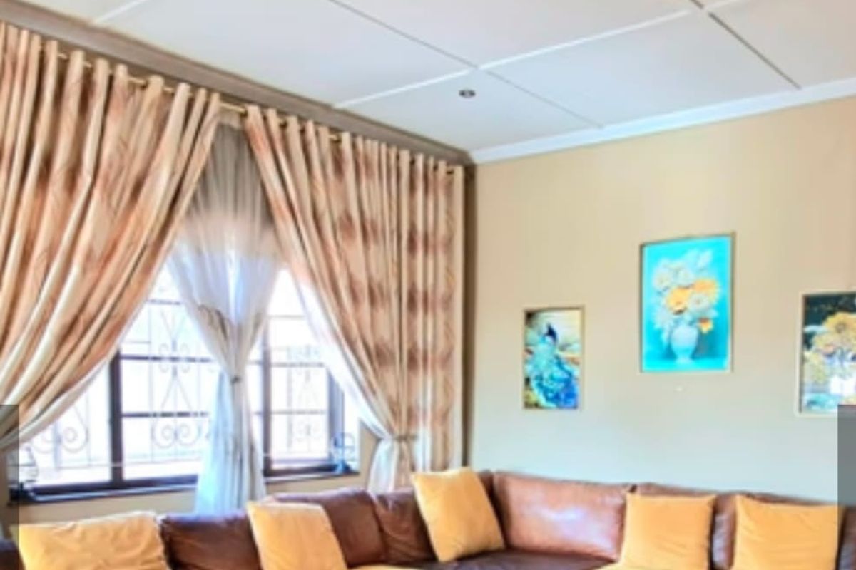 A comfortable living room featuring tiled flooring, recessed ceiling lighting, and large windows fitted with security burglar bars.