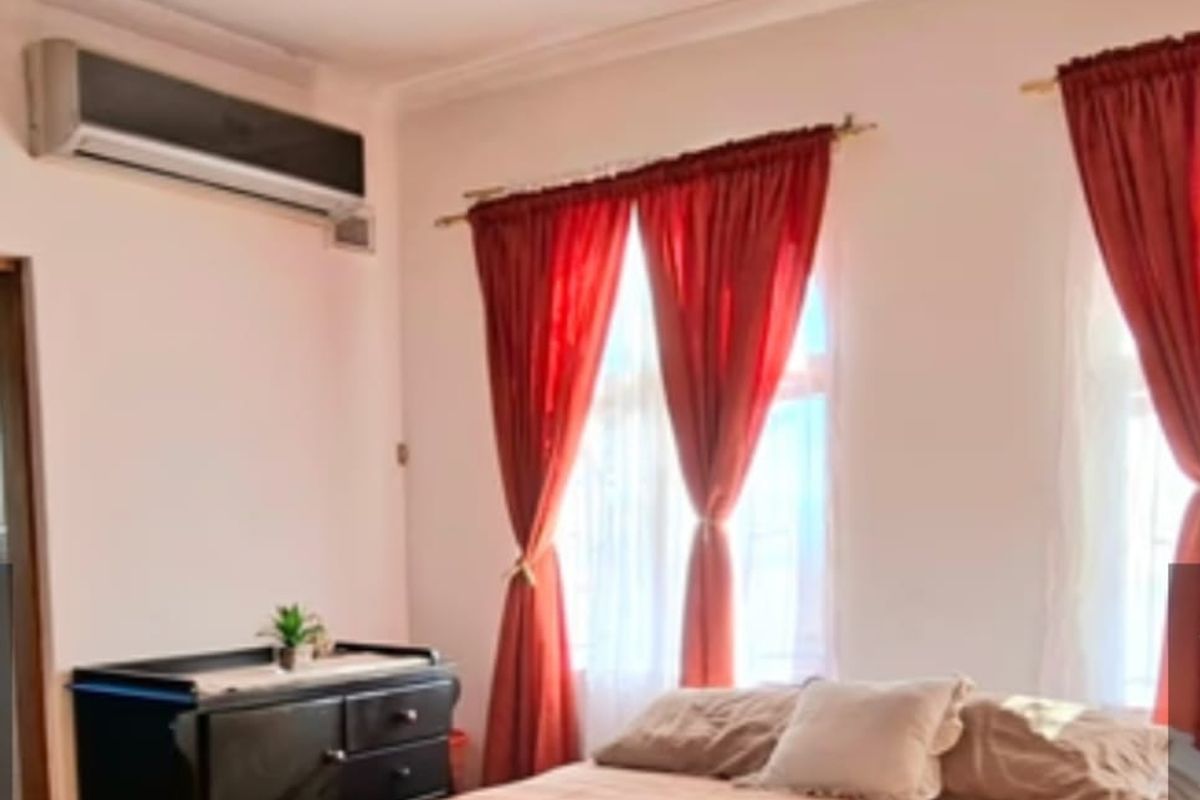 A bedroom featuring timber flooring, a split-system air conditioner, and natural light through dual windows.