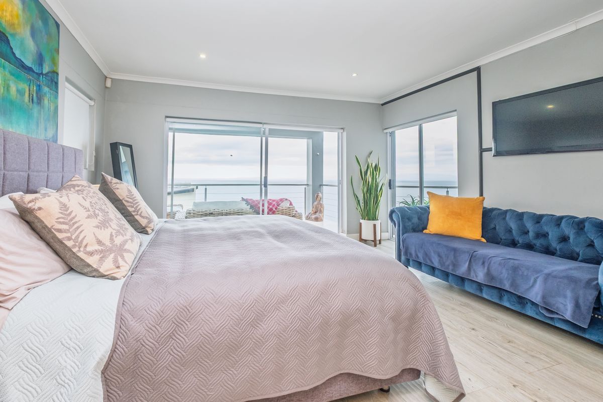Spacious bedroom featuring light laminate flooring, recessed lighting, and large sliding glass doors providing direct access to a balcony with ocean views.
