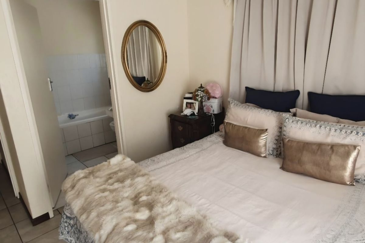 A bedroom featuring tiled flooring and direct access to an en-suite bathroom with a bathtub.