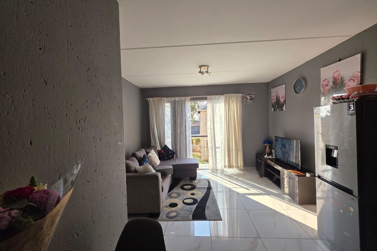 Open plan living area featuring polished tiled flooring and a sliding glass door providing natural light and access to the exterior.