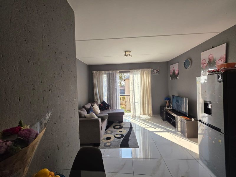 Open plan living area featuring polished tiled flooring and a sliding glass door providing natural light and access to the exterior.