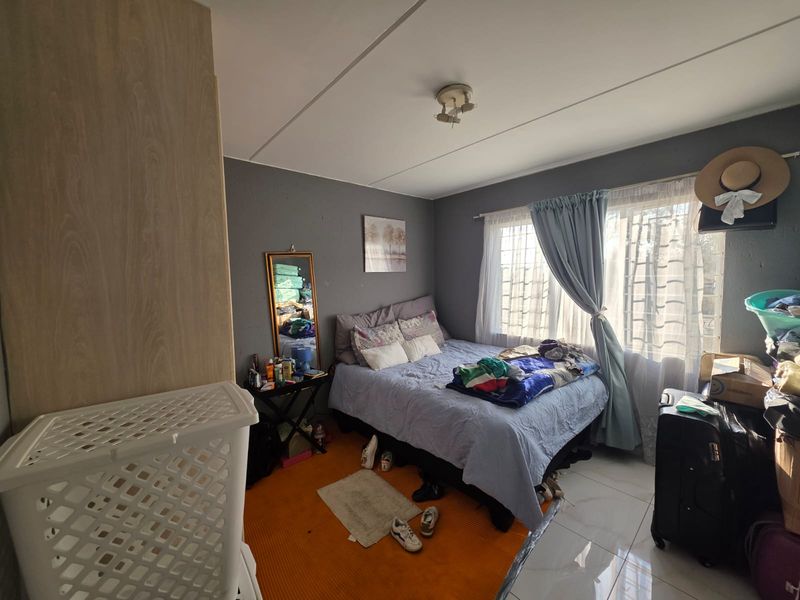 A bedroom featuring tiled flooring, a built-in wardrobe, and natural light through the window.