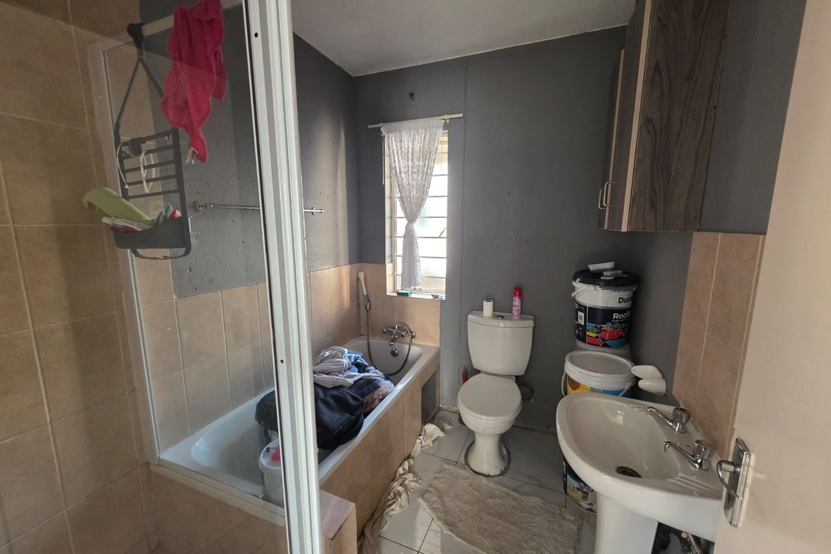A functional bathroom featuring a bathtub, pedestal basin, and toilet, with tiled finishes and wall-mounted storage cabinetry.