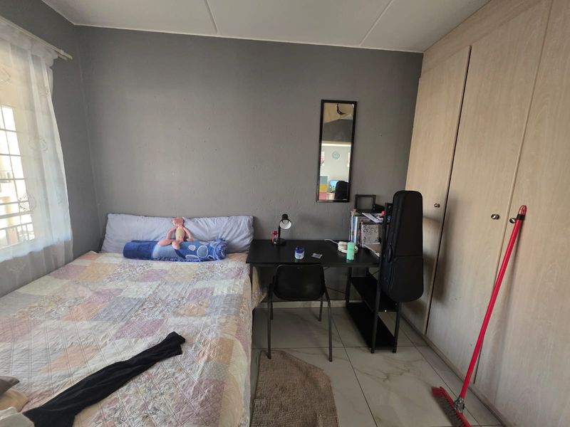 A functional bedroom featuring tiled flooring and built-in cupboards, providing essential storage space.