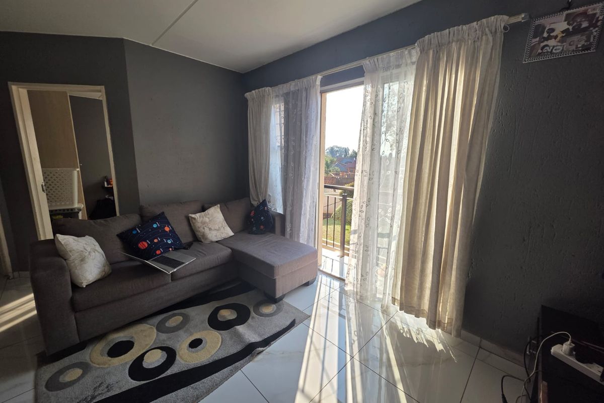 Living room featuring tiled flooring and a sliding glass door providing direct access to a balcony, allowing for natural light.