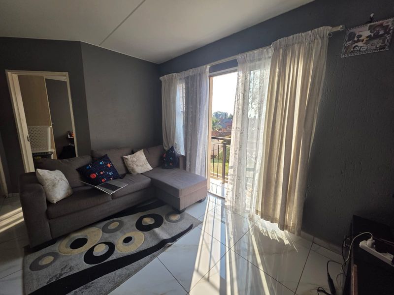 Living room featuring tiled flooring and a sliding glass door providing direct access to a balcony, allowing for natural light.