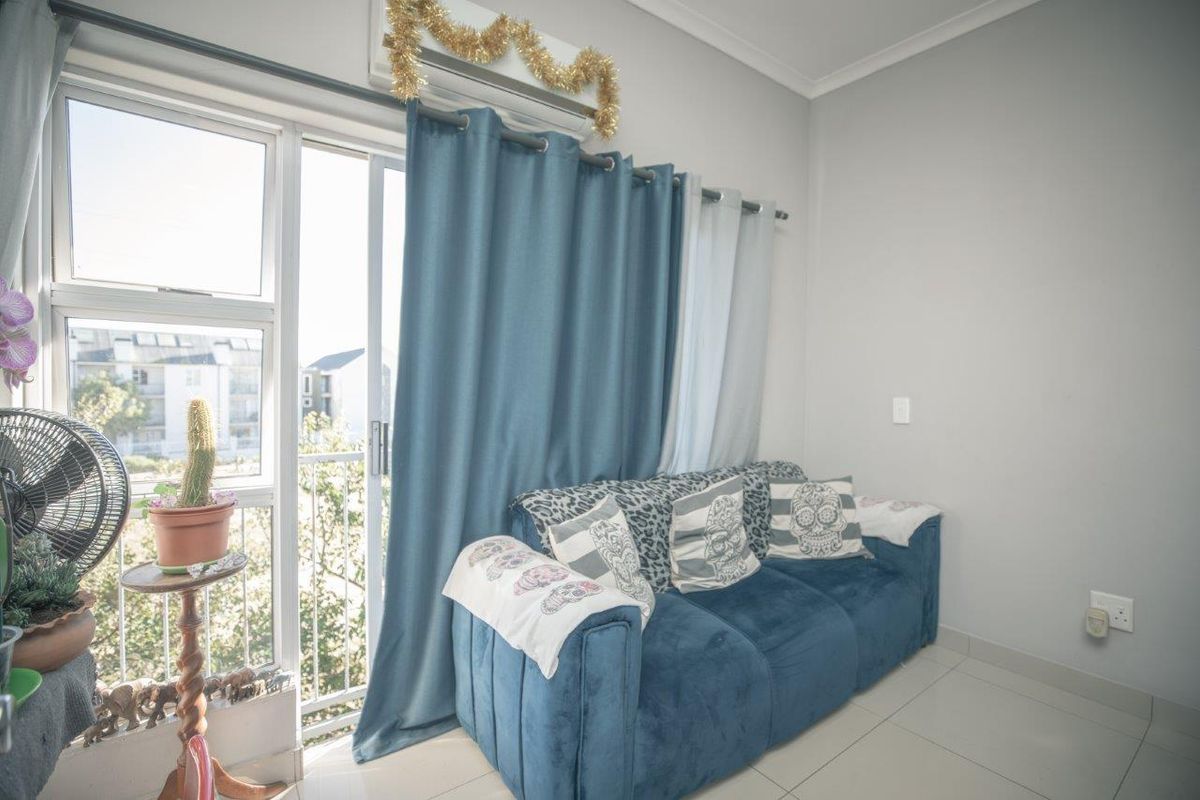 A bright living room featuring tiled flooring, an air conditioning unit, and a sliding glass door providing access to a balcony.