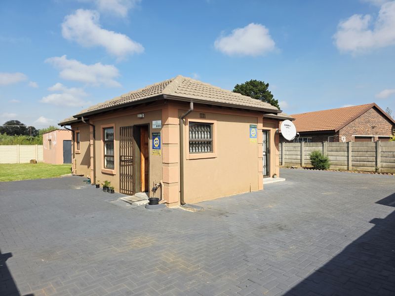 A well-maintained single-story house featuring a tiled roof, paved driveway, and secure access points with security gates and bars.