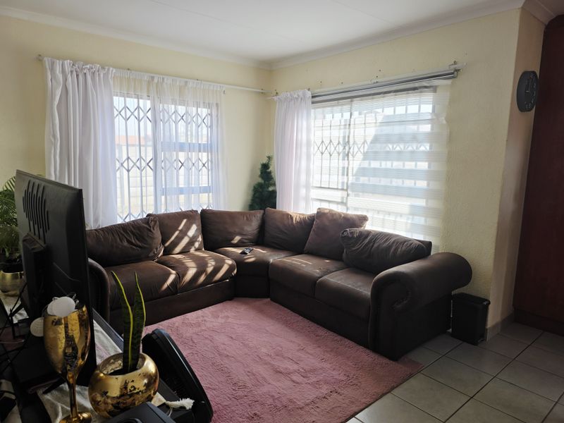 A living room featuring tiled flooring and security gates on the windows, providing a functional and secure space.