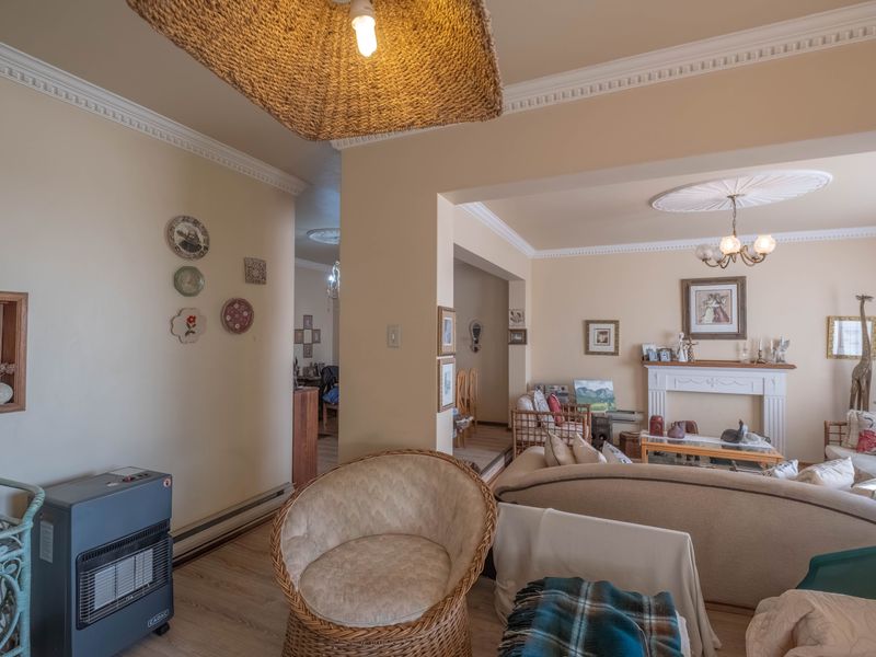 A spacious living room featuring a classic fireplace mantel, decorative crown molding, and ceiling roses, providing a traditional foundation for the living area.
