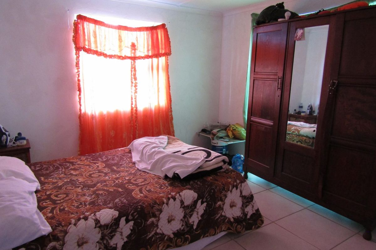 A bedroom featuring tiled flooring and basic finishes, offering a functional space that could benefit from modern updates and improved lighting.