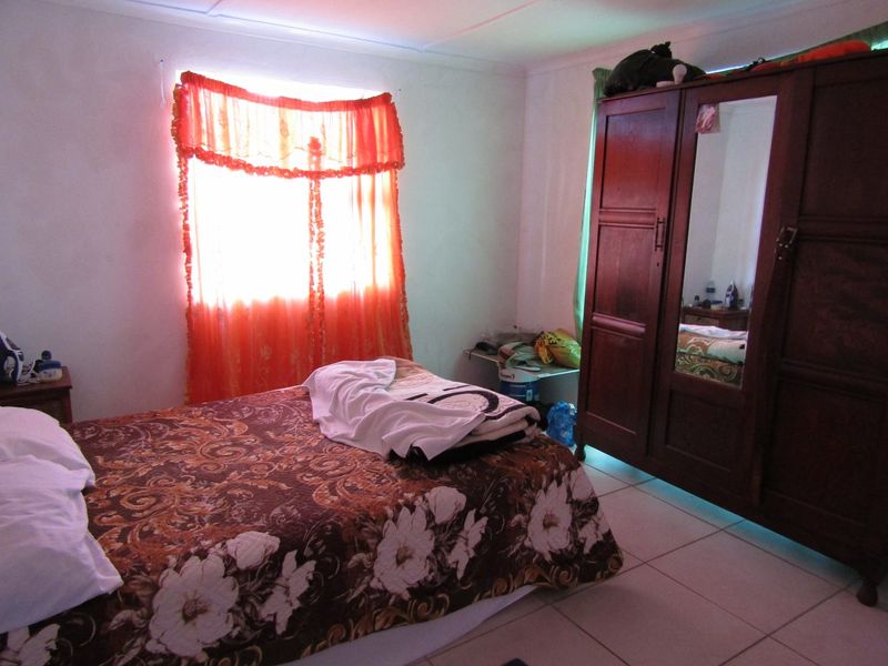 A bedroom featuring tiled flooring and basic finishes, offering a functional space that could benefit from modern updates and improved lighting.