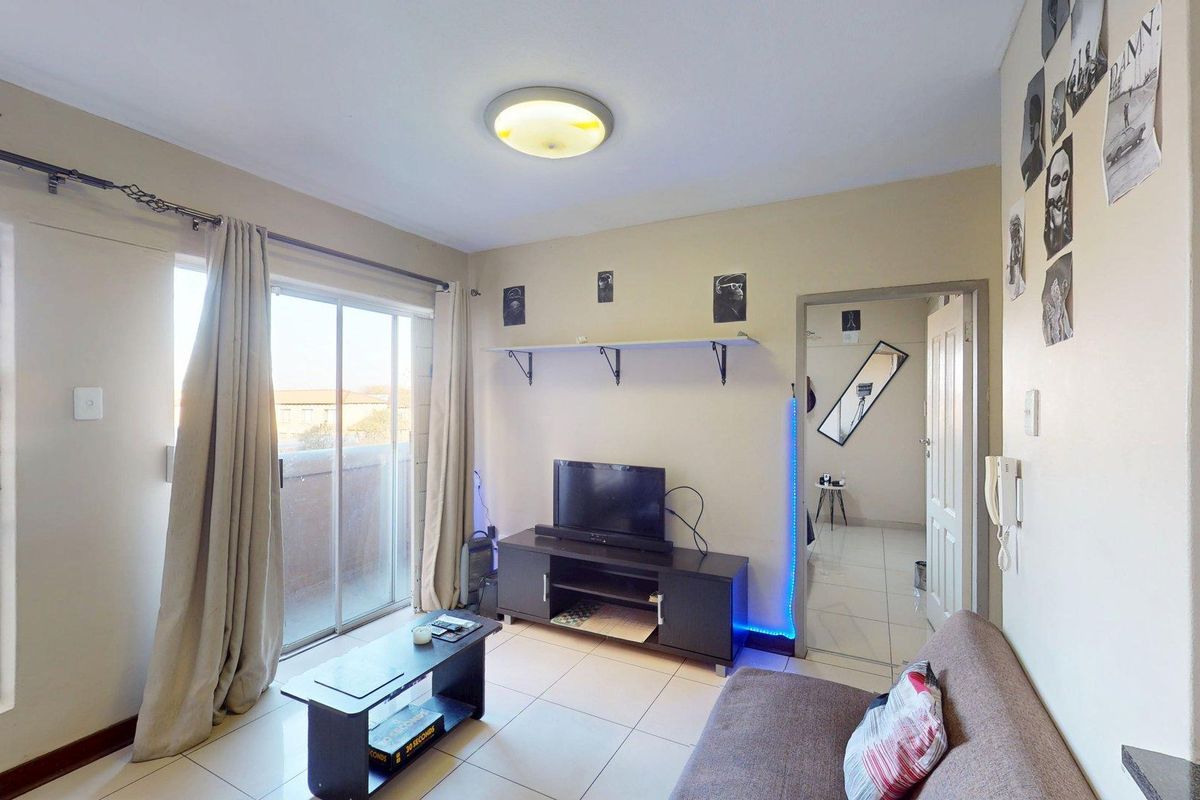 A living room featuring tiled flooring, a sliding glass door leading to a balcony, and an intercom system.