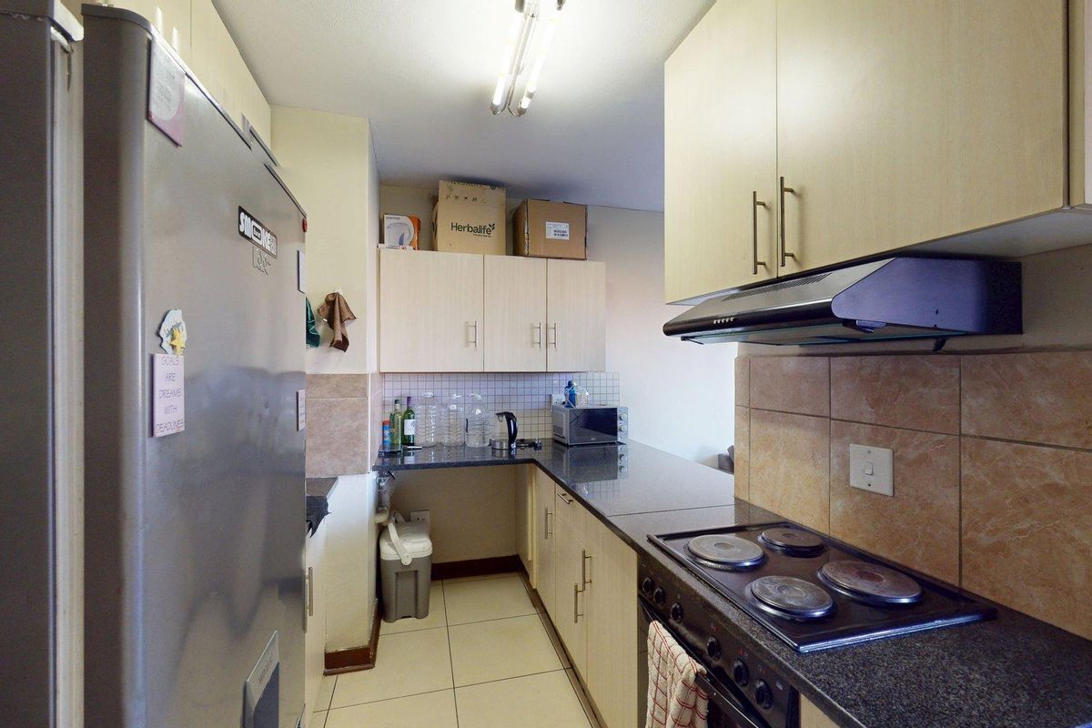 A functional kitchen featuring built-in cabinetry, granite countertops, an electric stove with an extractor fan, and tiled finishes throughout.