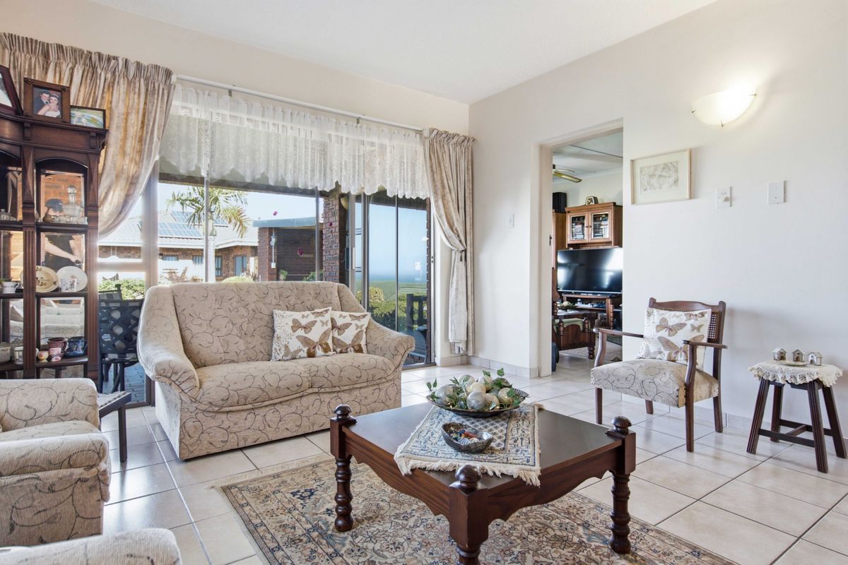A bright living room featuring tiled flooring and large sliding glass doors that provide access to the outdoor area and natural light.