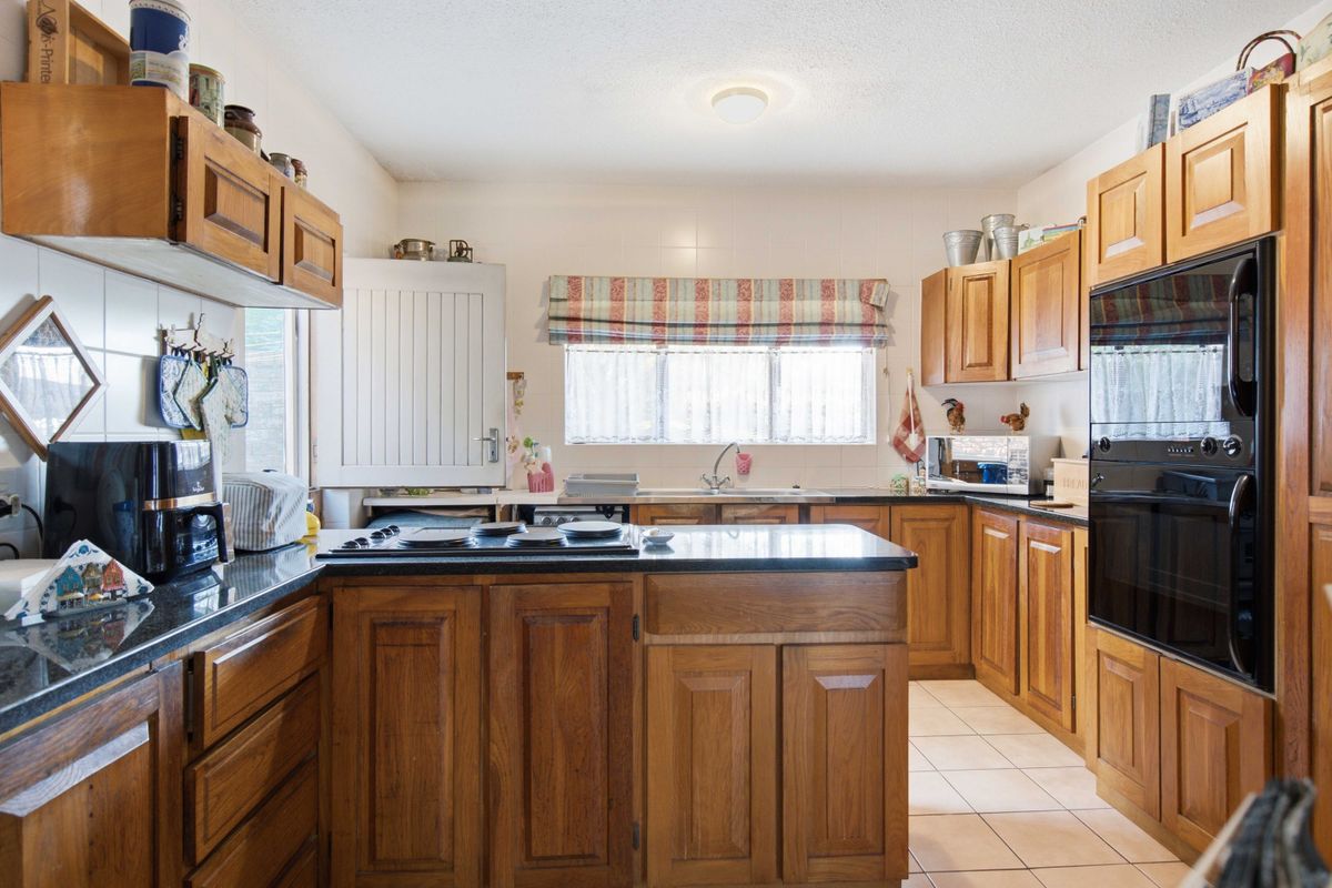 A functional kitchen featuring traditional wooden cabinetry, granite countertops, a built-in oven, and a tiled backsplash, offering a classic aesthetic with practical storage.