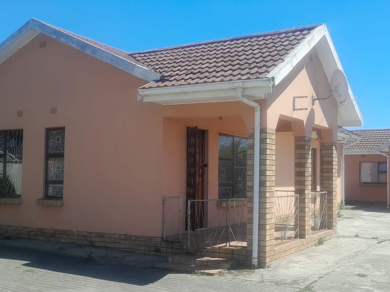 Front elevation of a single-story house featuring a tiled roof, brick pillar entrance, and a paved driveway area.