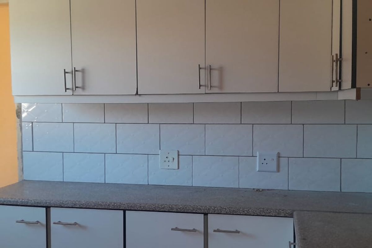 A functional kitchen area featuring white cabinetry, a speckled laminate countertop, and a clean white subway tile backsplash.
